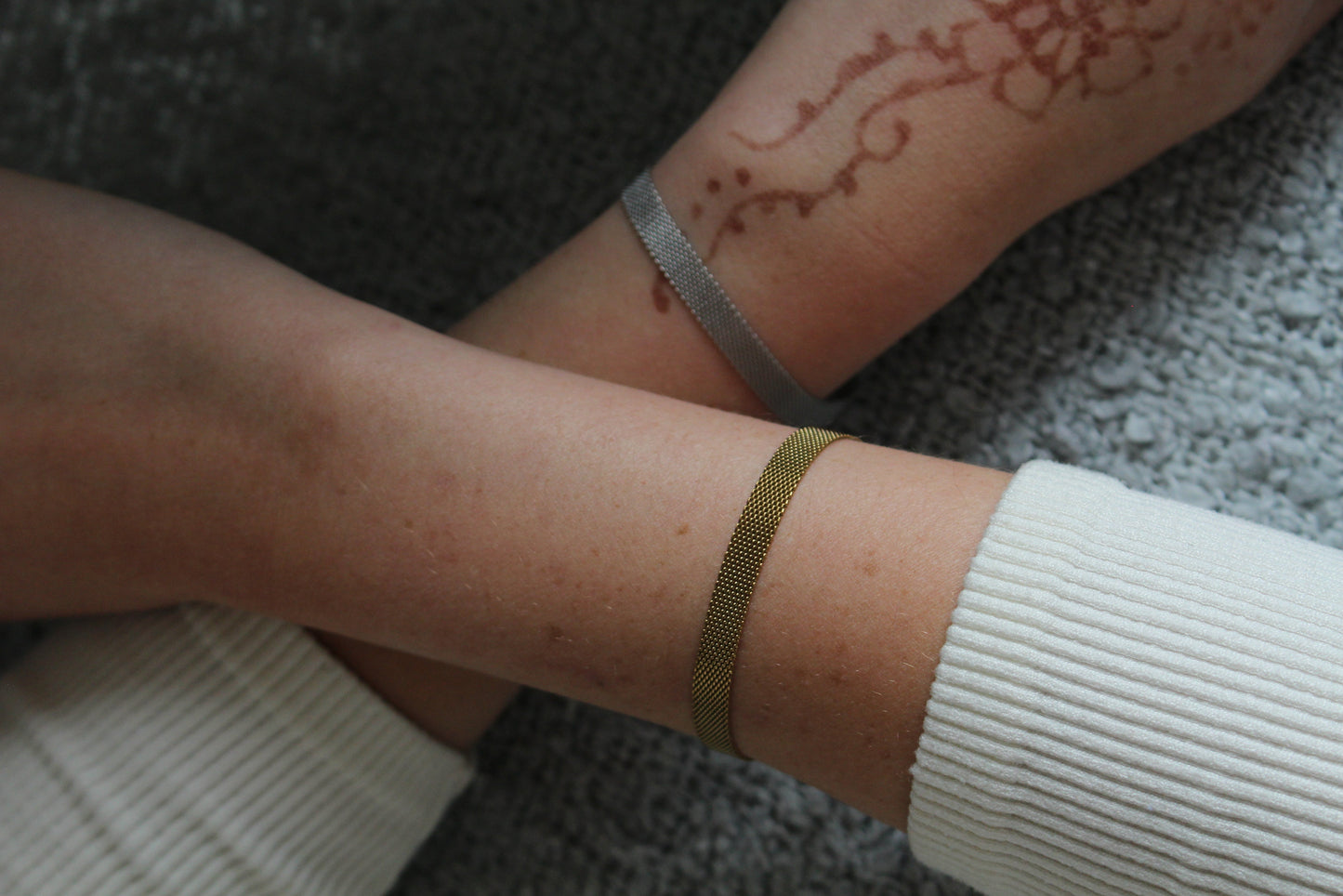 Close-up of a person's arm with a gold bracelet on a textured surface