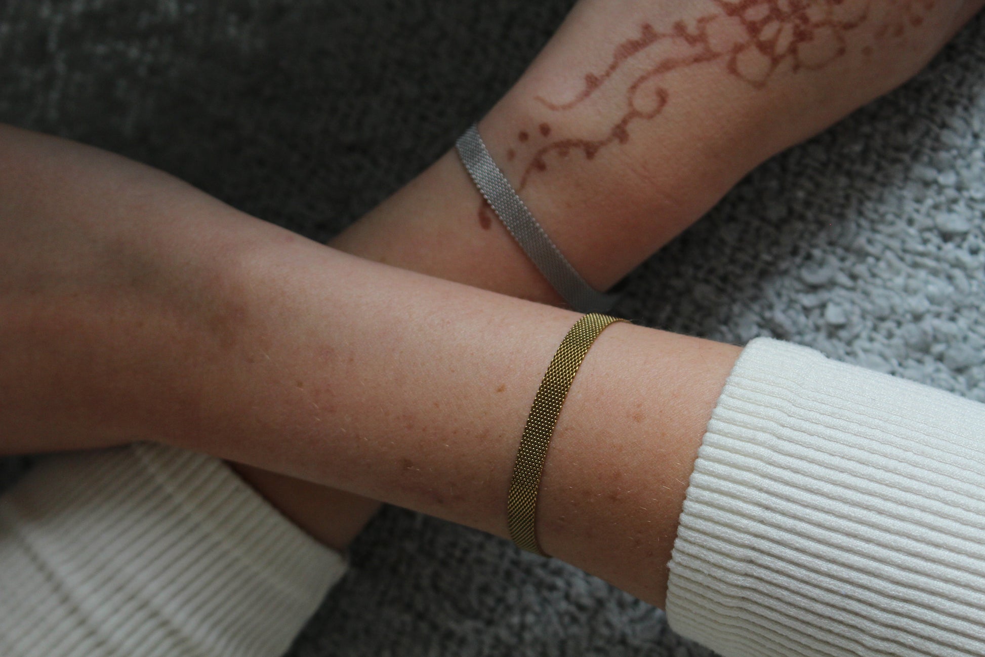 Close-up of a person's arm with a gold bracelet on a textured surface